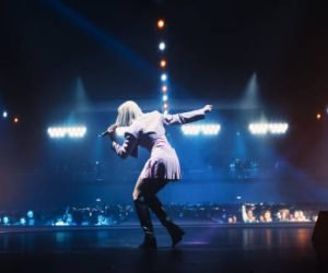 Music Contest: Back View of a Pop Music Artist Performing a Hit Song on Stage in Front of a Sold-Out Audience. Her Charismatic Stage Presence and Lyrics Electrify the Diverse Music Fans
